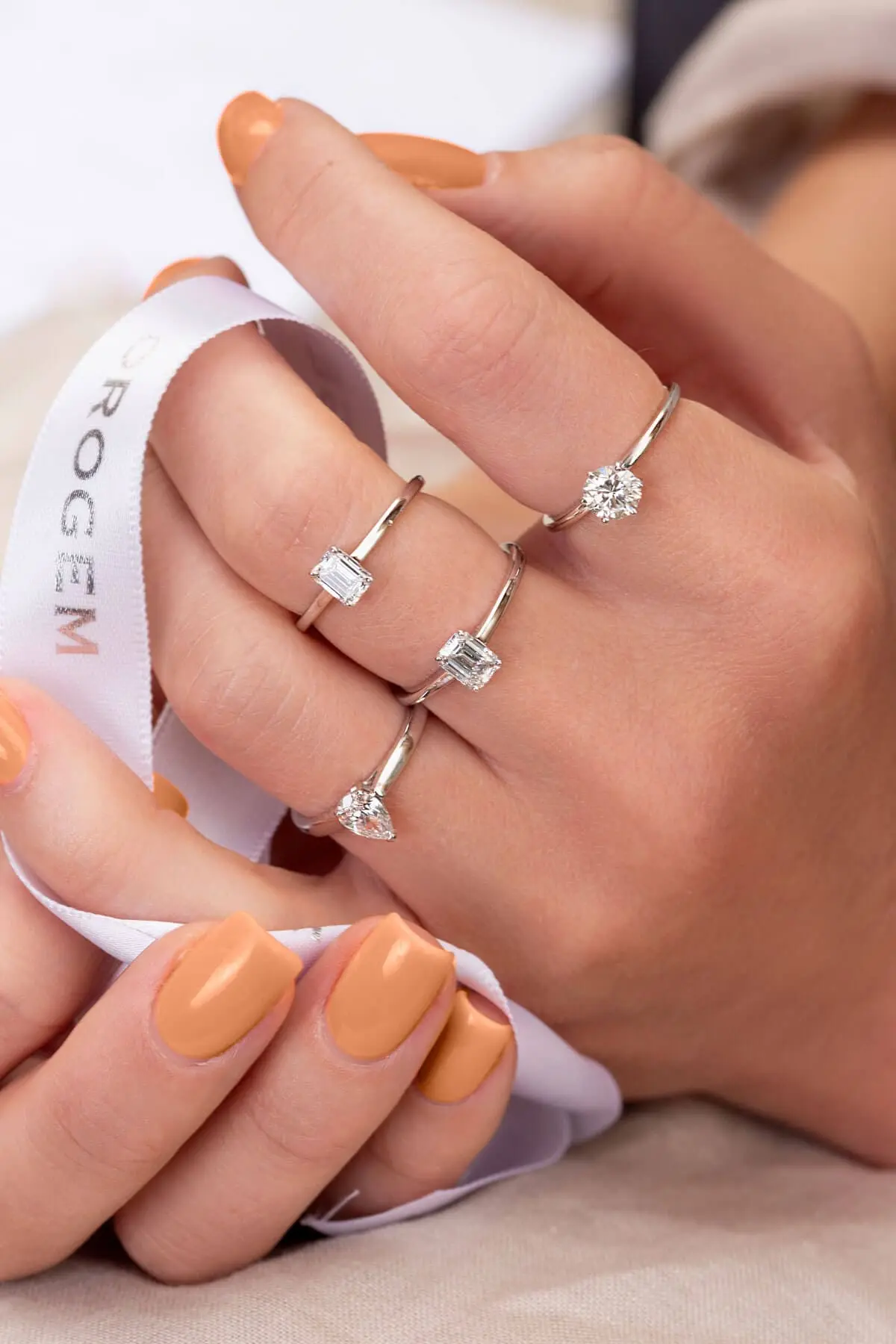 Hand met diamanten verlovingsringen en Orogem lint